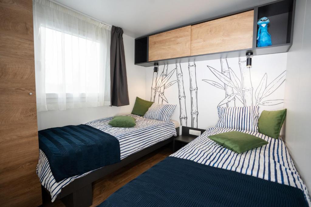 科兰Luxury mobile home LA ISLA BONITA, Terra Park SpiritoS的一间卧室设有两张床和窗户。