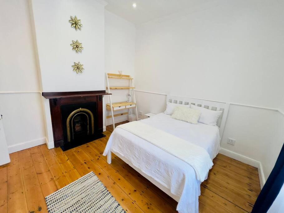 开普敦Modern Victorian 4 bedroom home in trendy Observatory.的卧室配有白色的床和壁炉