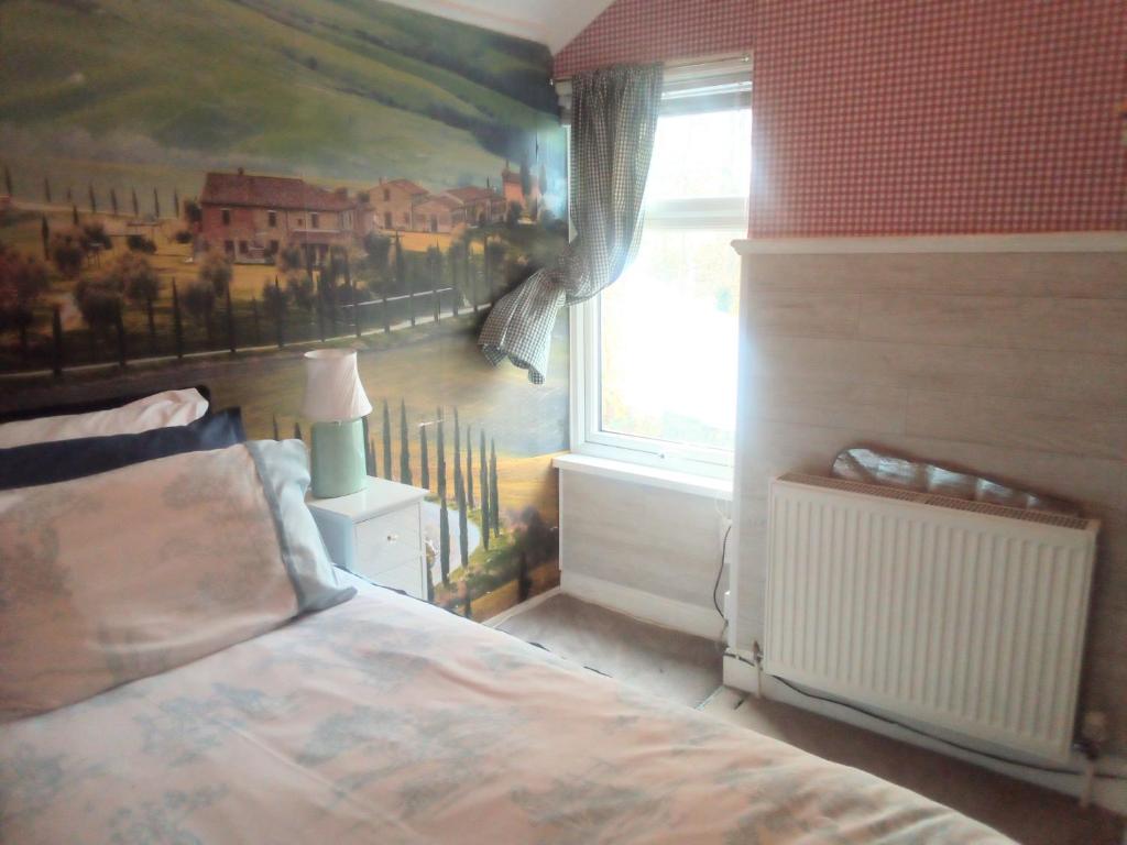卡迪夫Homestay Cardiff的卧室配有一张床,墙上挂有绘画作品