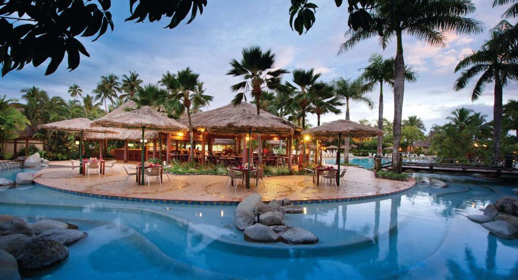 克罗托格奥瑞格斐济海滩度假酒店的度假村的游泳池配有桌子和遮阳伞