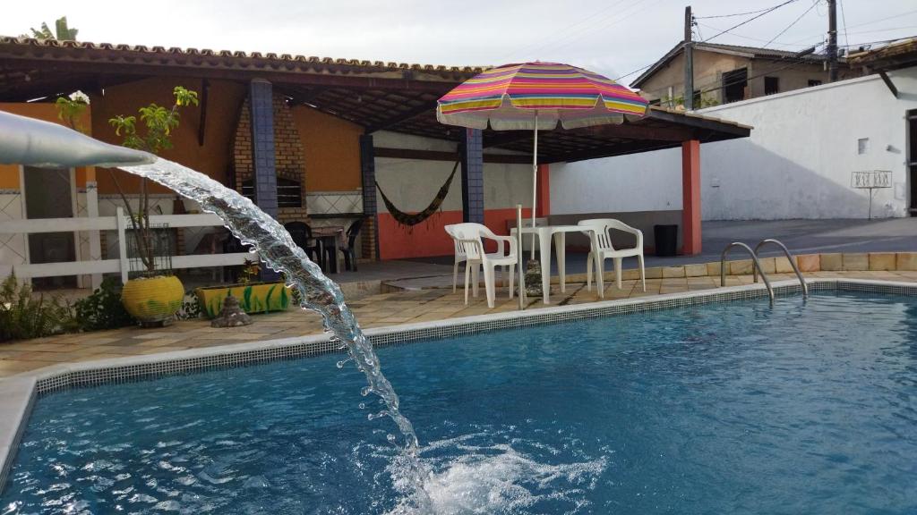 萨尔瓦多Diversão, churrasco e piscina - Praia de Ipitanga的一个带遮阳伞和桌椅的游泳池