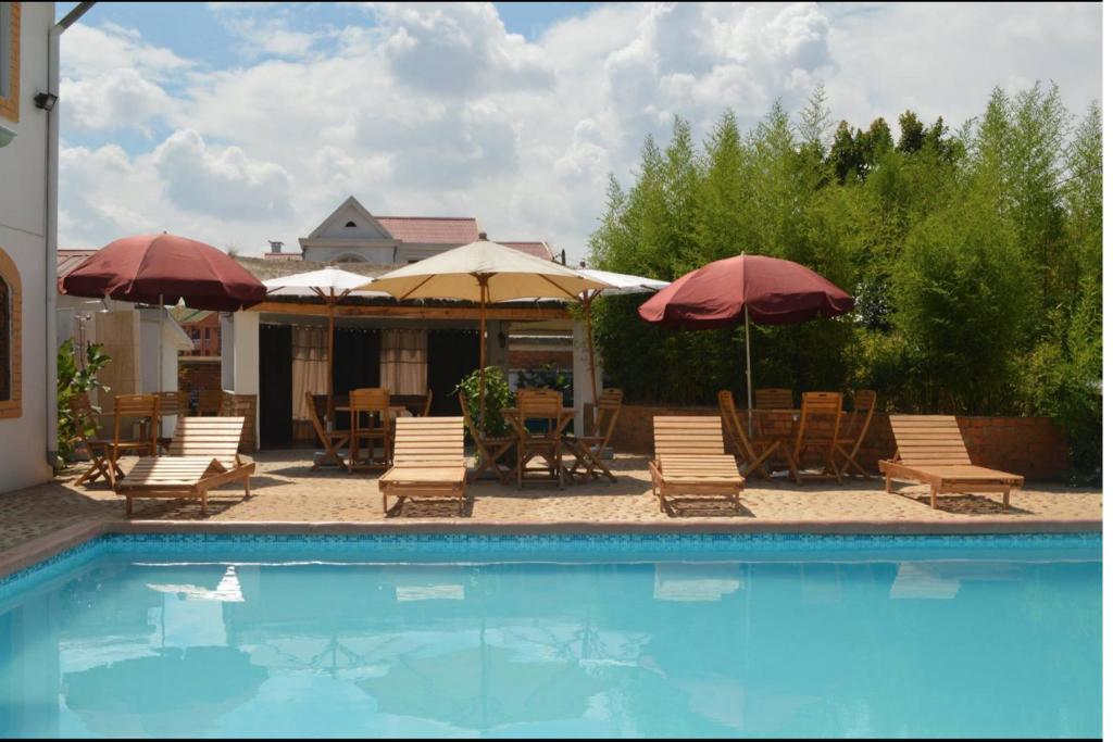 塔那那利佛意阿瑞姆巴托酒店的游泳池配有椅子、遮阳伞和桌子