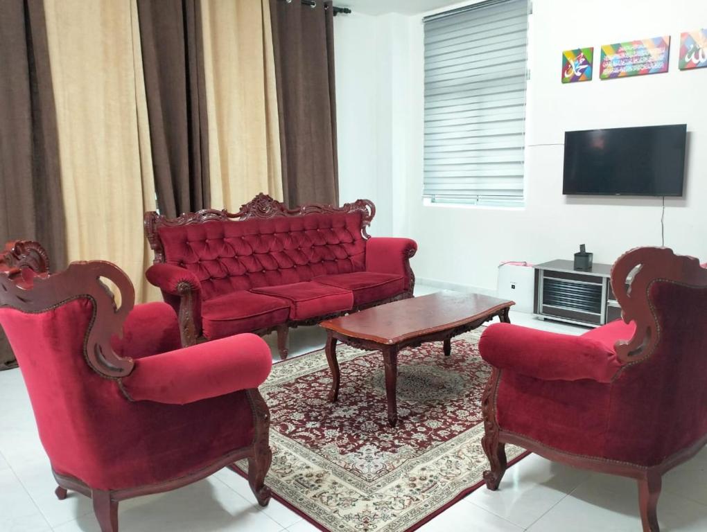 日得拉Mahzan Homestay的客厅配有红色的沙发和两把椅子