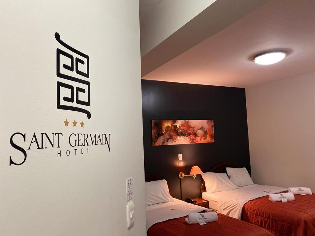 特鲁希略Saint Germain Hotel的酒店客房设有两张床,墙上有标志