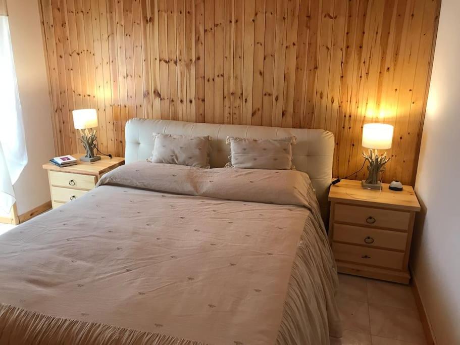 RovereAccogliente casa con camino in stile montano的一间卧室配有一张带2个床头柜的大床