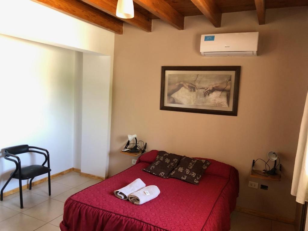 圣胡安Excelente Duplex en Consorcio Privado c/ cochera的一间卧室配有一张带红色床罩和椅子的床
