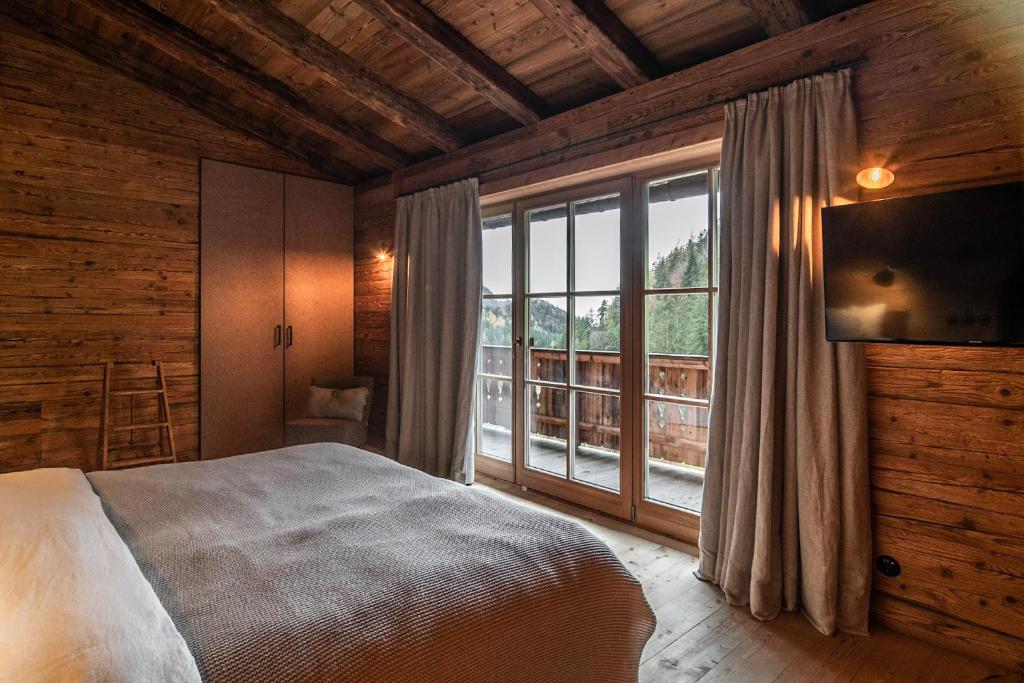 凯撒山麓舍福Luxury old wood mountain chalet in a sunny secluded location with gym, sauna & whirlpool的一间卧室设有一张床和一个大窗户