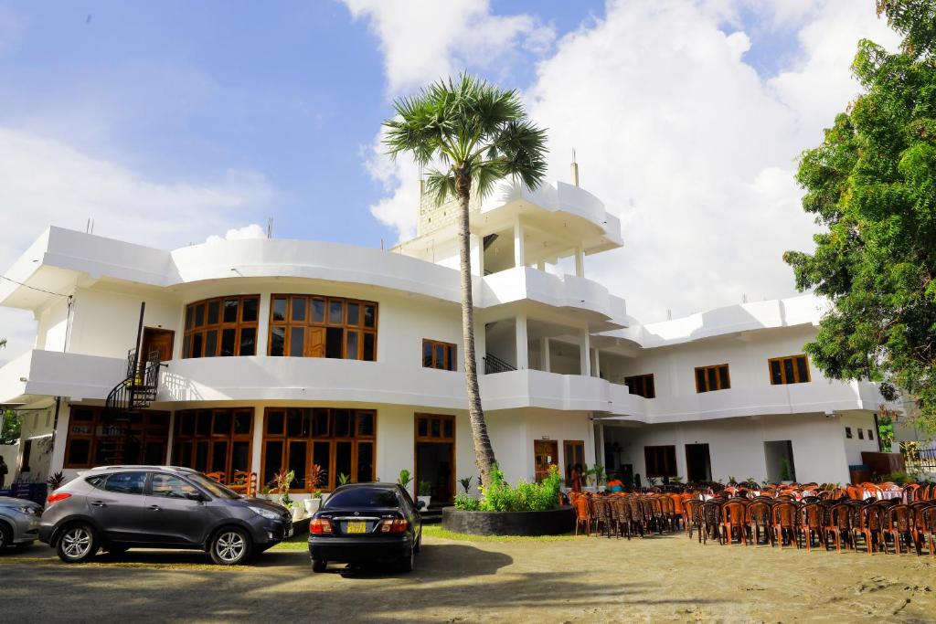 贾夫纳Amis Hotel & Restaurant的一座白色的建筑,前面有棕榈树