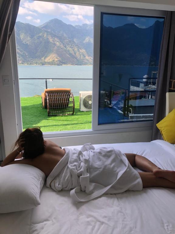 圣佩德罗拉拉古纳luxury atitlan suites的躺在窗前床边的女人