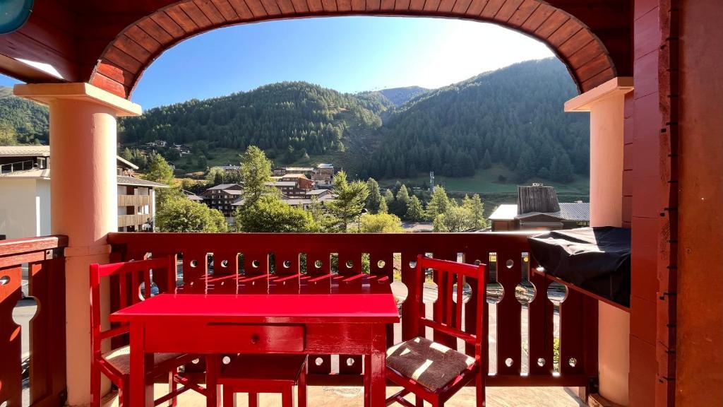 拉富la foux d'allos au pied des pistes的阳台上配有红色的桌椅,享有风景。