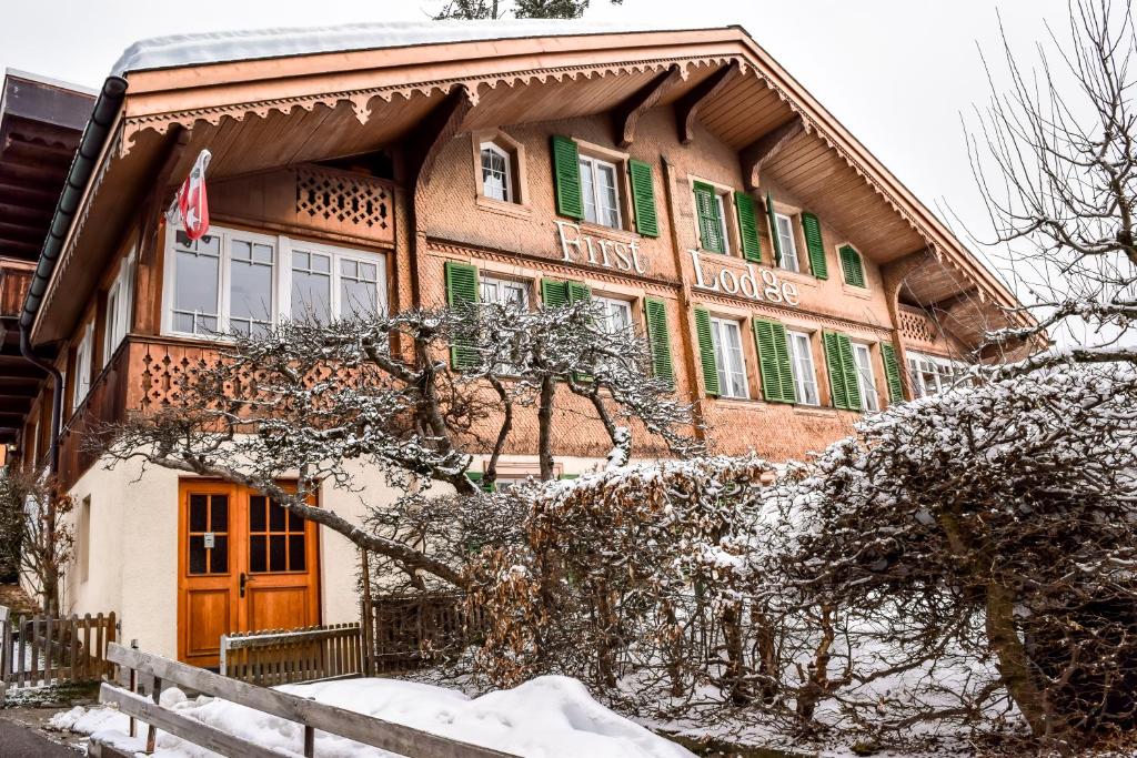 格林德尔瓦尔德First Lodge的一座大建筑,在雪地上设有绿色百叶窗