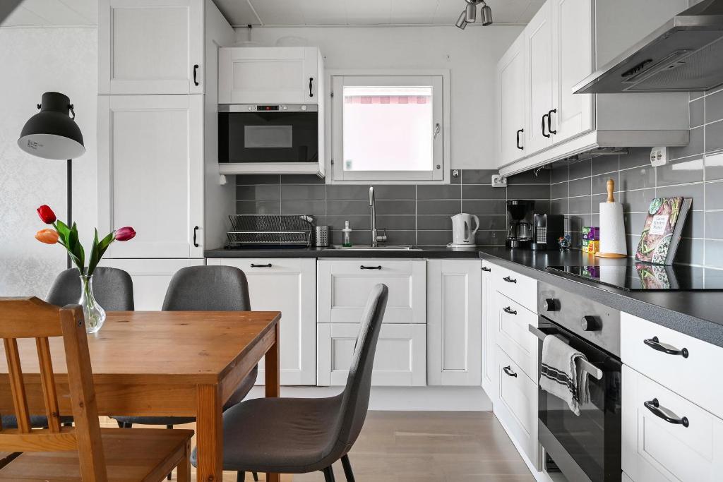 斯德哥尔摩Sparkling modern house in Kista - close to city的厨房配有白色橱柜和木桌