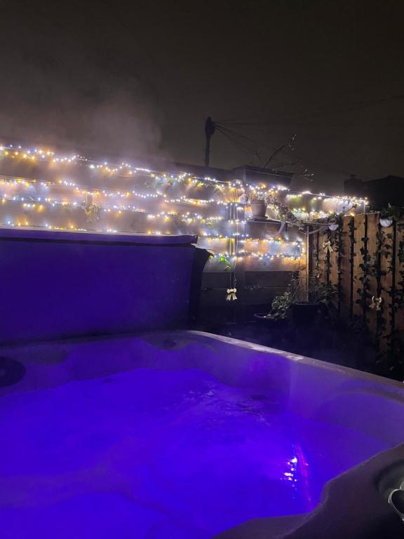 彭里斯Honeysuckle Cottage & Whinfell Studio的夜间在围栏上设有灯光的热水浴池
