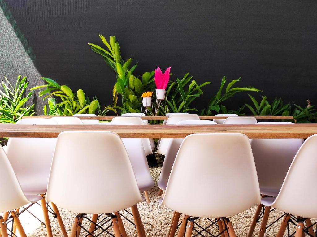 圣塔特蕾莎海滩ICO Living Hostel的一张带白色椅子的会议桌和一朵粉红色的花