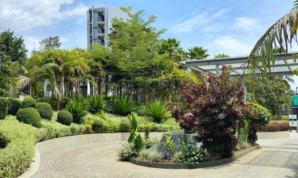 基加利Century Park Hotel & Residences的一座种植了许多植物和树木的花园,一座建筑