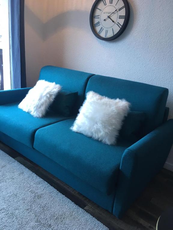 蒂涅Studio 1 cabine chalet club III refait à neuf的蓝色的沙发,配有两个枕头,墙上挂着一个钟