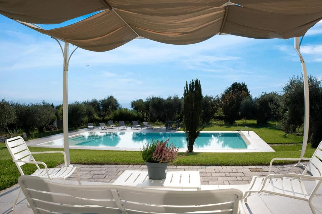 马内尔巴Villa Athena Charme的游泳池配有椅子和桌子及遮阳伞