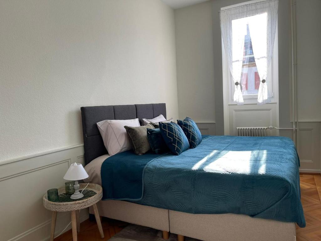 纳沙泰尔V&V CENTRE Neuchatel的一间卧室配有一张带蓝色床单的床和一扇窗户。