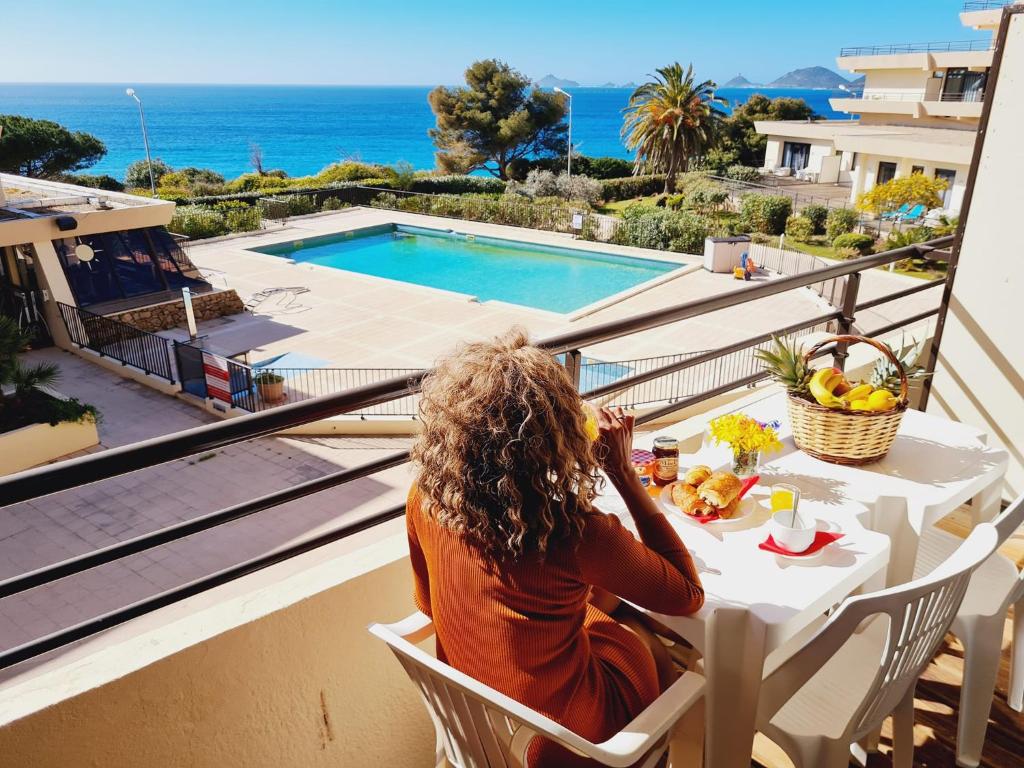 阿雅克修CosySeaside Corsica Ajaccio Piscine Terrasse Mer的坐在阳台上的桌子旁,欣赏海洋美景的女人