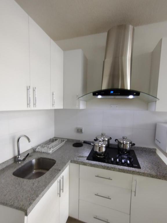皮乌拉Suites Apart Piura的白色的厨房配有炉灶和水槽