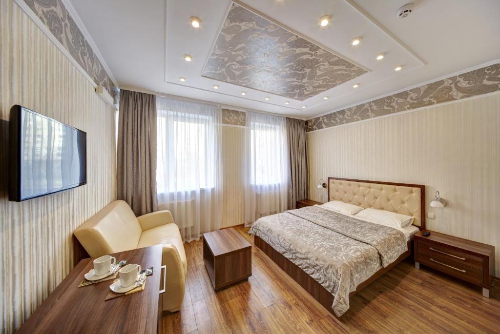 利沃夫三冠酒店 的一间卧室配有一张床、一张桌子和一台电视。