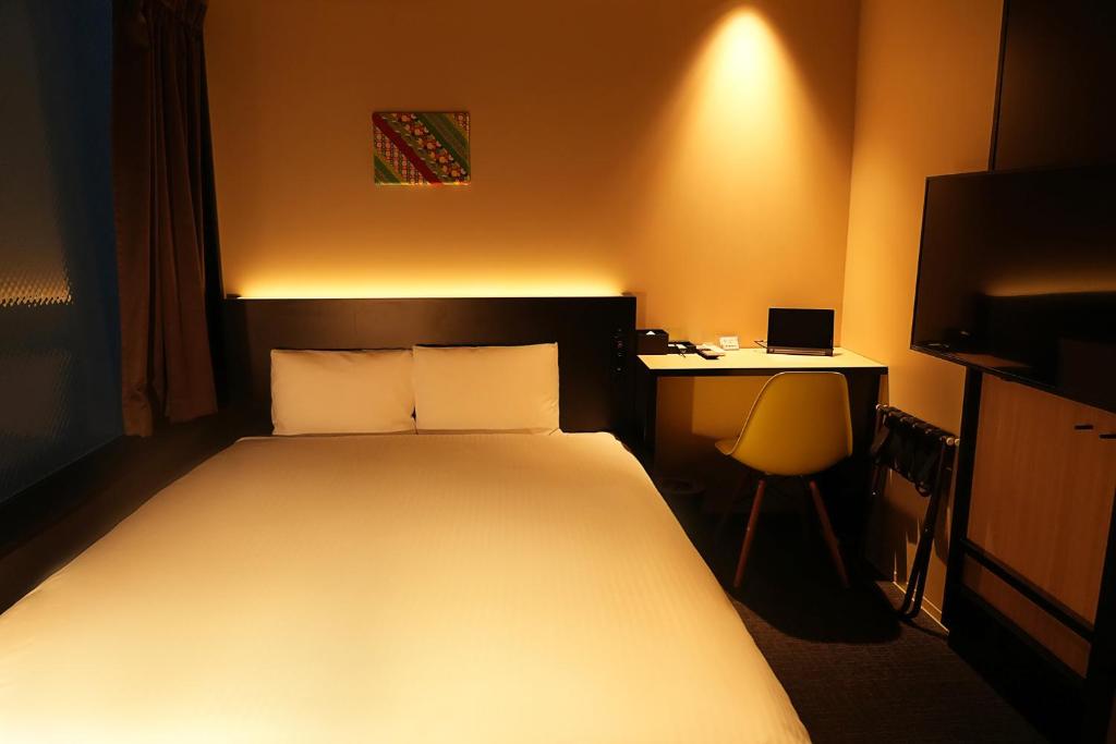 东京东京东神田秋叶原N+酒店的一间卧室配有一张床和一张带笔记本电脑的书桌