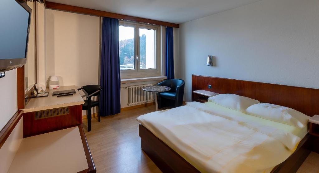 巴登Hotel Linde - 24h Self Check-in的配有一张床、一张书桌和一扇窗户的酒店客房