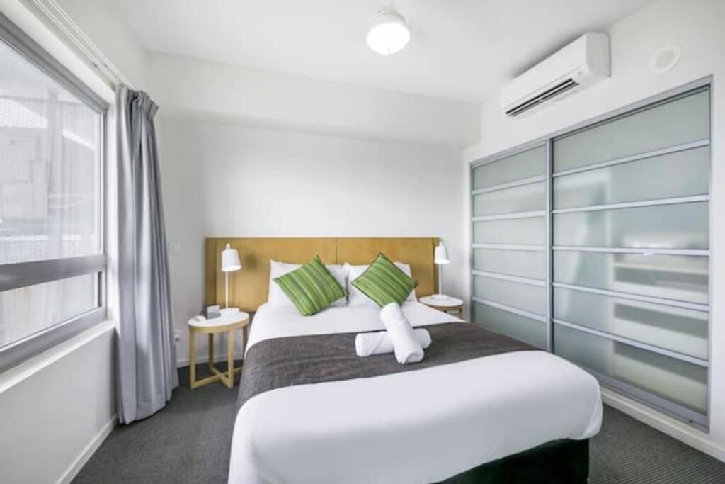 达尔文Pandanas 15th floor (Water, City & Sunset views)的一间卧室配有一张带绿色枕头的大床