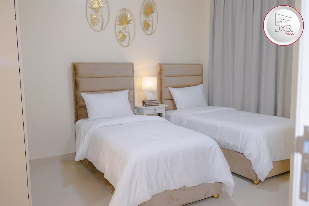迪拜5 bedroom Villa - Dubai Hills的一间卧室配有两张带白色床单的床