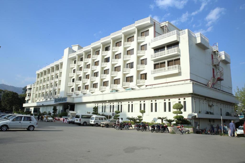 伊斯兰堡Hotel Hillview Islamabad的一座白色的大建筑,前面有汽车停放
