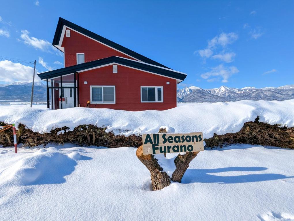 富良野All Seasons Furano Chalet的红房子前雪中的标志