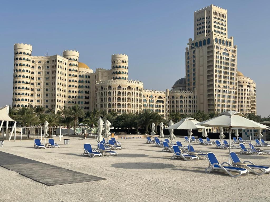 拉斯阿尔卡麦Private Suites Al Hamra Palace at golf & sea resort的海滩上设有椅子和遮阳伞,还有建筑