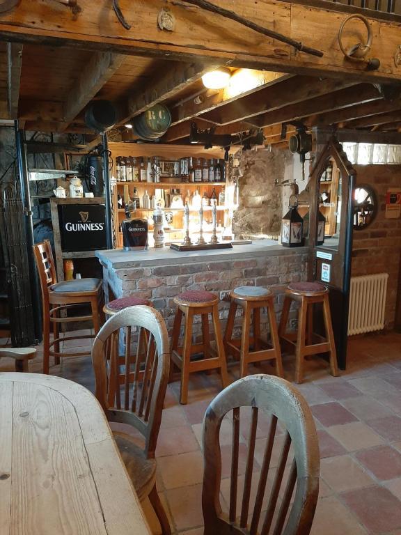 卡林福德Nellie's Farmhouse的酒吧配有木椅、桌子和柜台