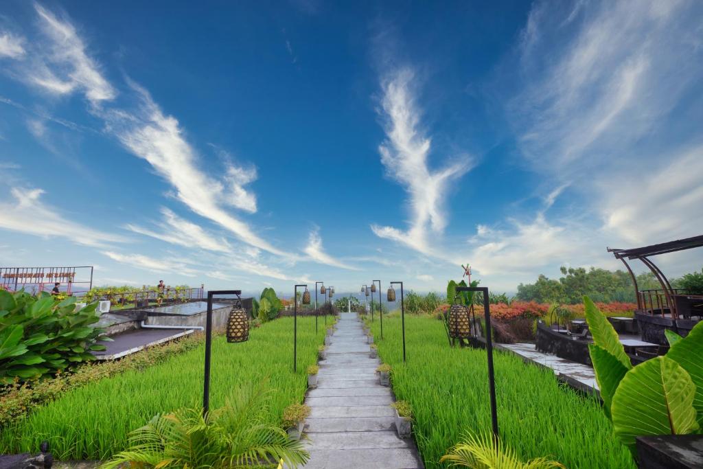 日惹Abhayagiri - Sumberwatu Heritage Resort的穿过一片蓝天的草地的路径