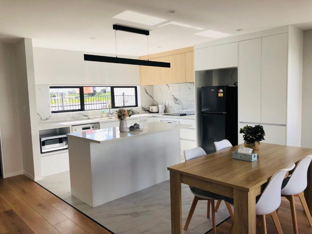 奥克兰Modern & Luxurious Home 3的白色的厨房配有木桌和桌椅