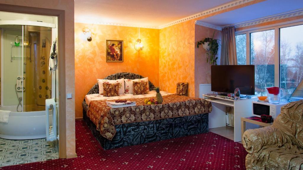 多莫杰多沃沃斯特克沃酒店的一间卧室配有一张床、一个浴缸和一台电视。