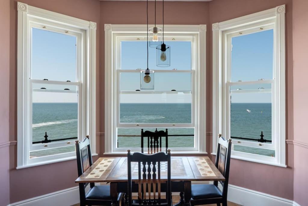 荷尼湾Stylish Beachfront Apartment, Sweeping Ocean Views and Luxury Touches的一间带桌子和四扇窗户的用餐室