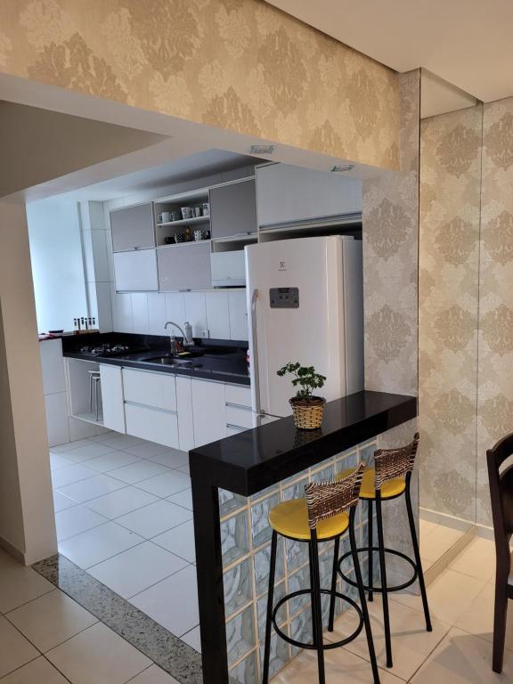 大普拉亚VISTA PRAIA MAR - AVIAÇÃO - 300 metros da praia - WI FI - VARANDA GOURMET com CHURRASQUEIRA - ESTACIONAMENTO gratuito的厨房配有黑色柜台和冰箱。