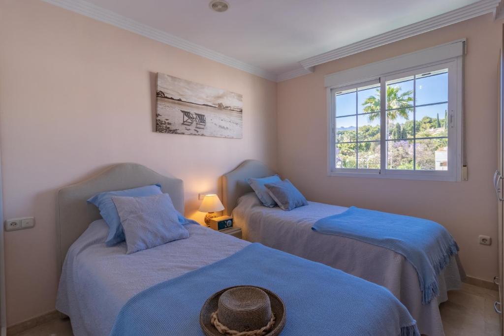 马贝拉Ático familiar con terraza y bonitas vistas al mar en Marbella - Rio Real 282G的客房设有两张带蓝色床单的床和窗户。