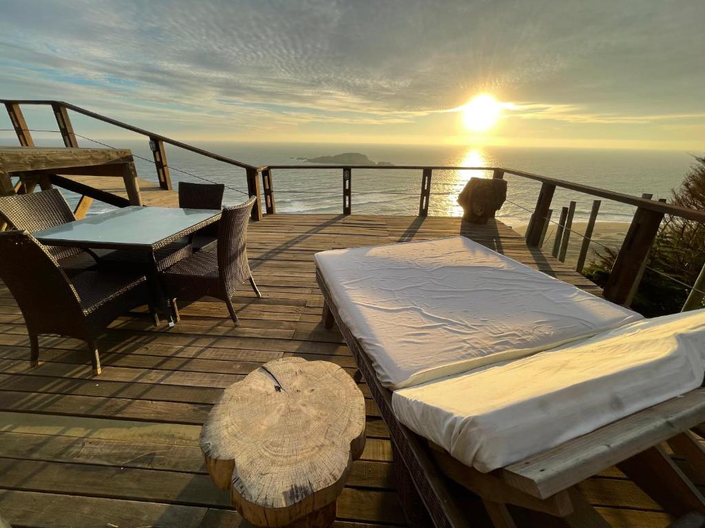马坦萨斯Mirada al Mar的木制甲板上配有一张床和一张桌子,享有日落美景