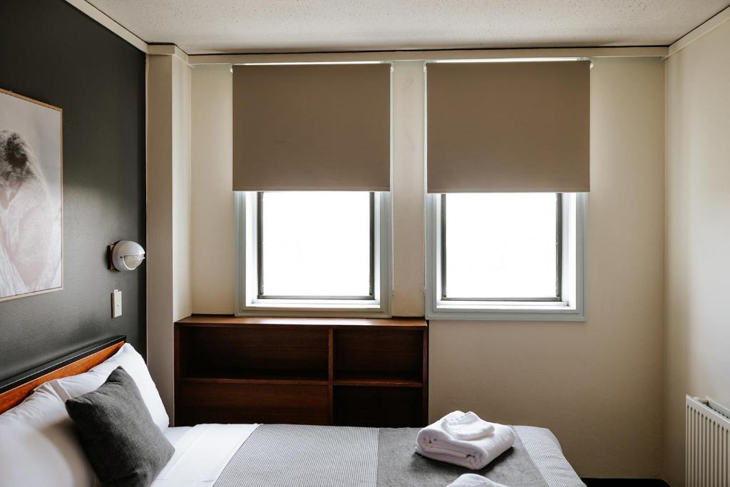 堪培拉Canberra Accommodation Centre的一间卧室设有2扇窗户和1张带毛巾的床