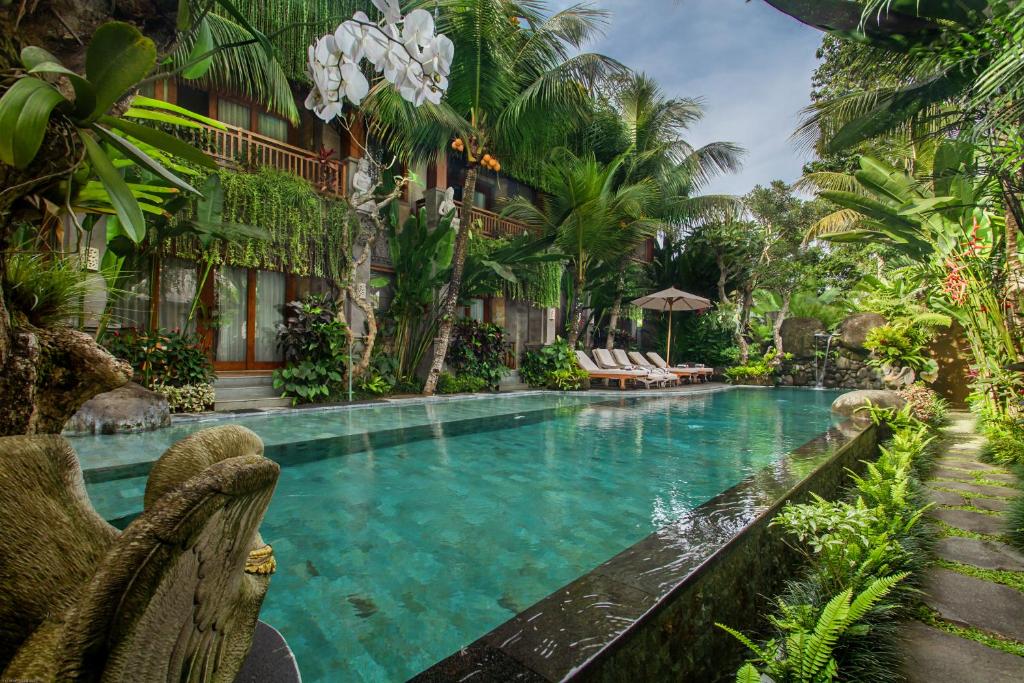 乌布Weda Cita Resort and Spa by Mahaputra的一个带椅子和棕榈树的度假村游泳池
