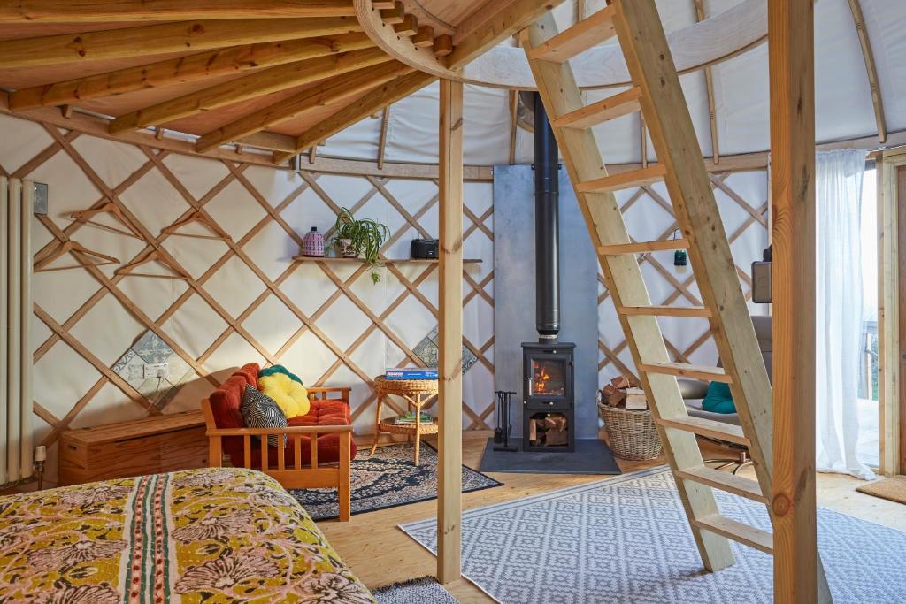 NitonPuckaster Cove Luxury Yurt的蒙古包内带一张床和一个壁炉的房间