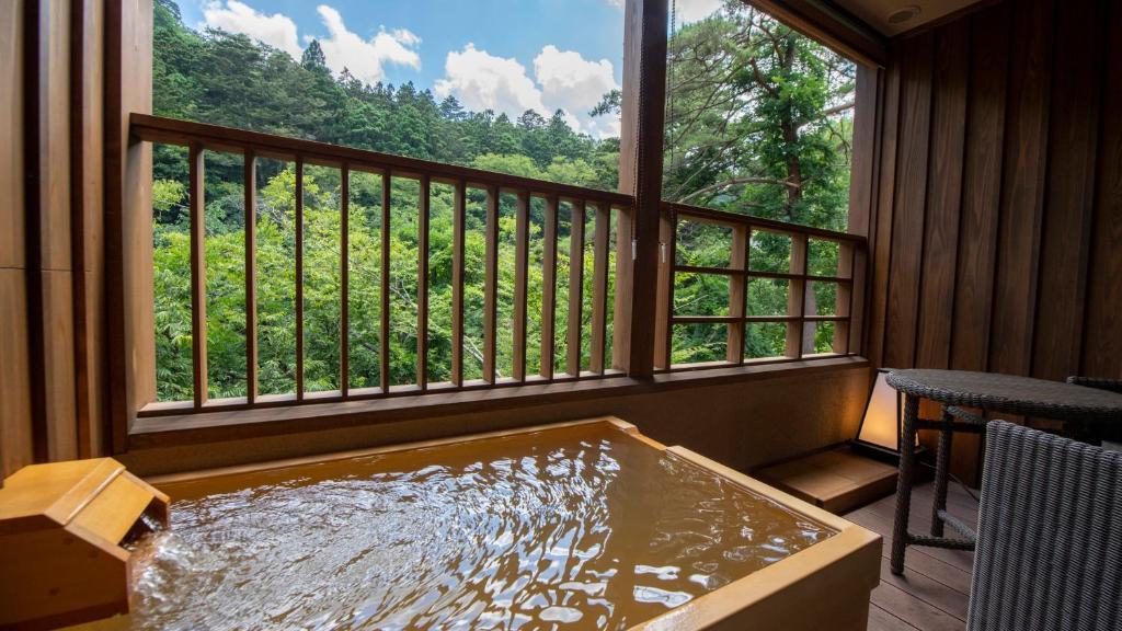 那须盐原市Shionoyu Onsen Rengetsu的带大窗户的客房内的热水浴池
