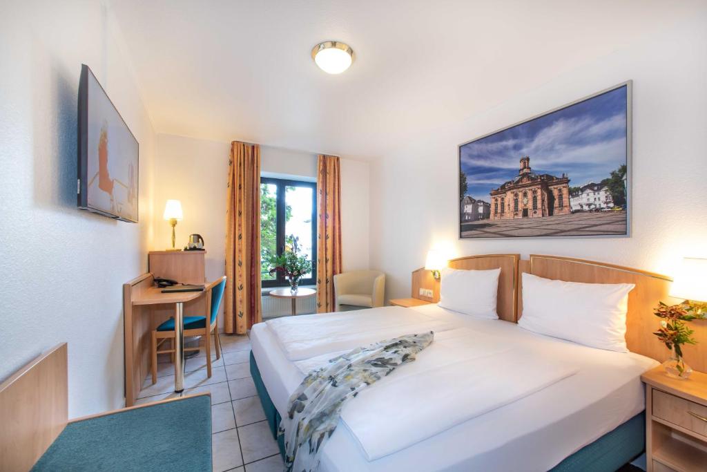 萨尔路易斯UNO Hotel Posthof Saarlouis的配有一张床和一张书桌的酒店客房