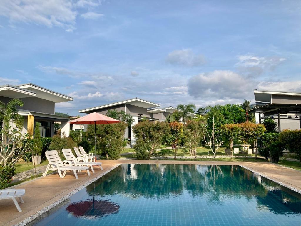 蔻立Oneandaman Resort的一个带两把椅子的游泳池以及一座房子