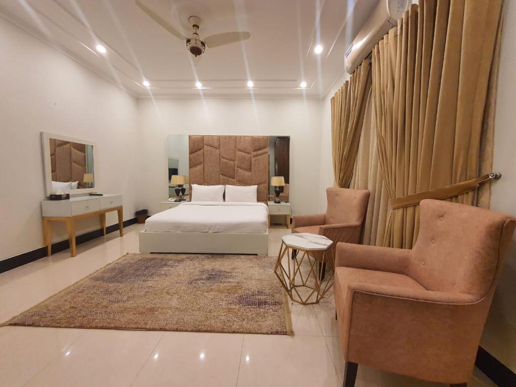 伊斯兰堡Margalla Hills Residency Islamabad Guest House的一间卧室配有一张床和两把椅子
