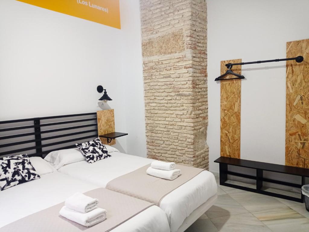 加的斯Planeta Cadiz Hostel的卧室配有白色大床和砖墙