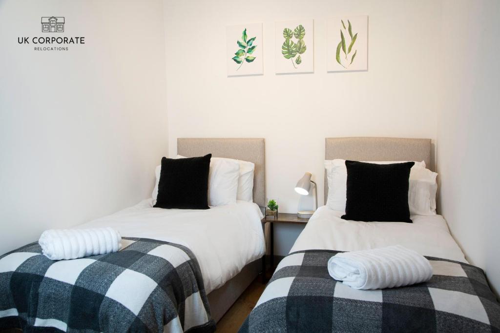 沃灵顿2 bed Apartment by UK Corporate Relocations Ltd的两张睡床彼此相邻,位于一个房间里