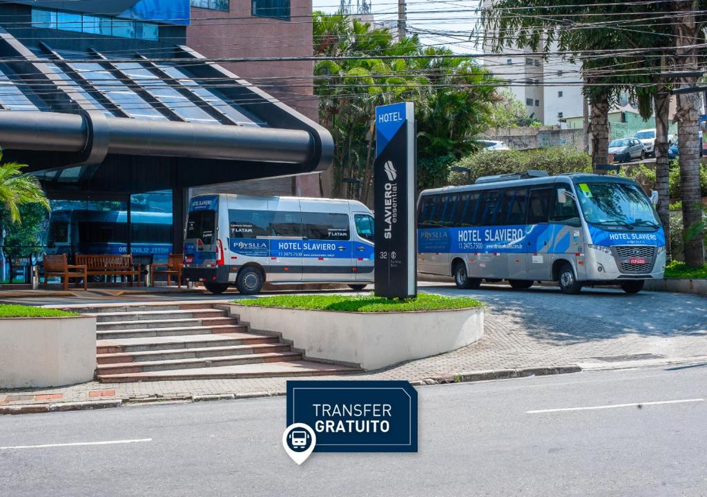 瓜鲁柳斯Slaviero Guarulhos Aeroporto的两辆巴士停在一个公共汽车站